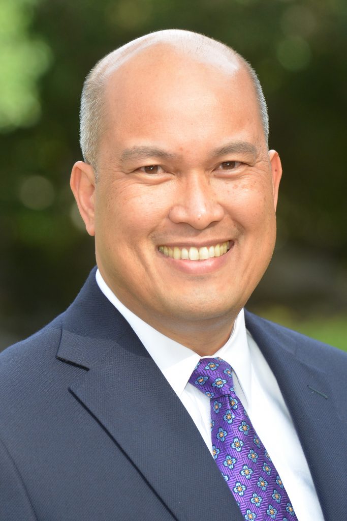 Photograph of Sam Bersola in a suit with a purple tie