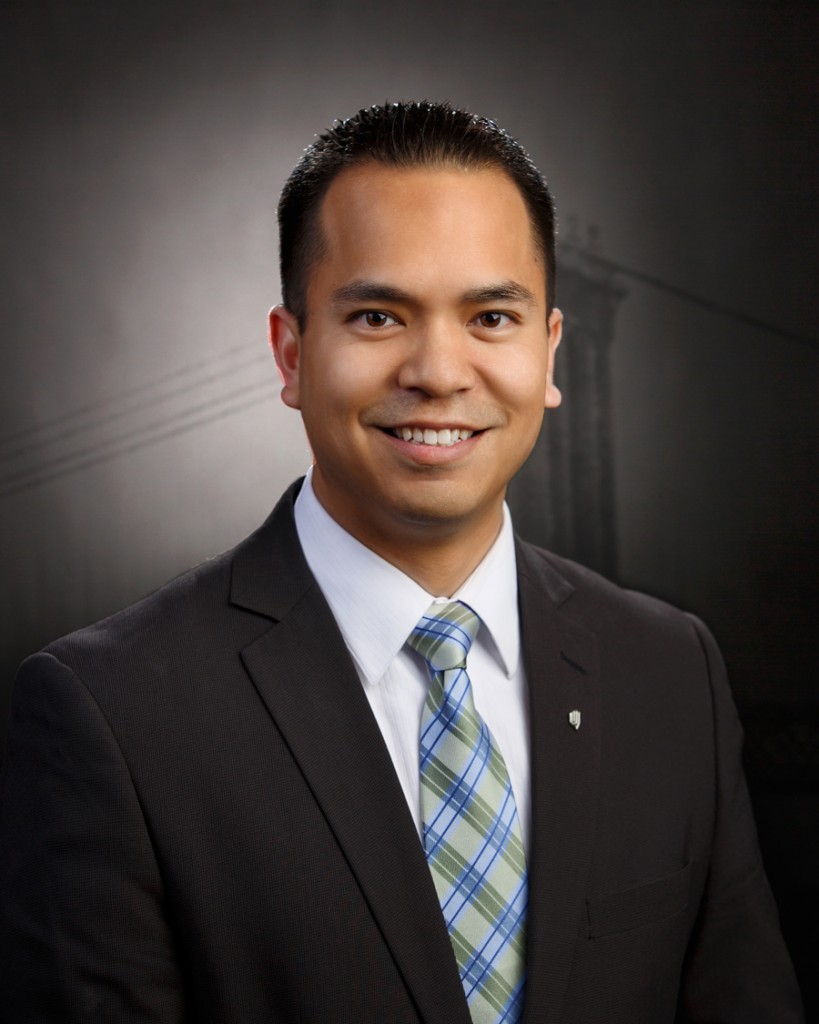 Photograph of Kyle Reyes wearing a dark suit and blue tie