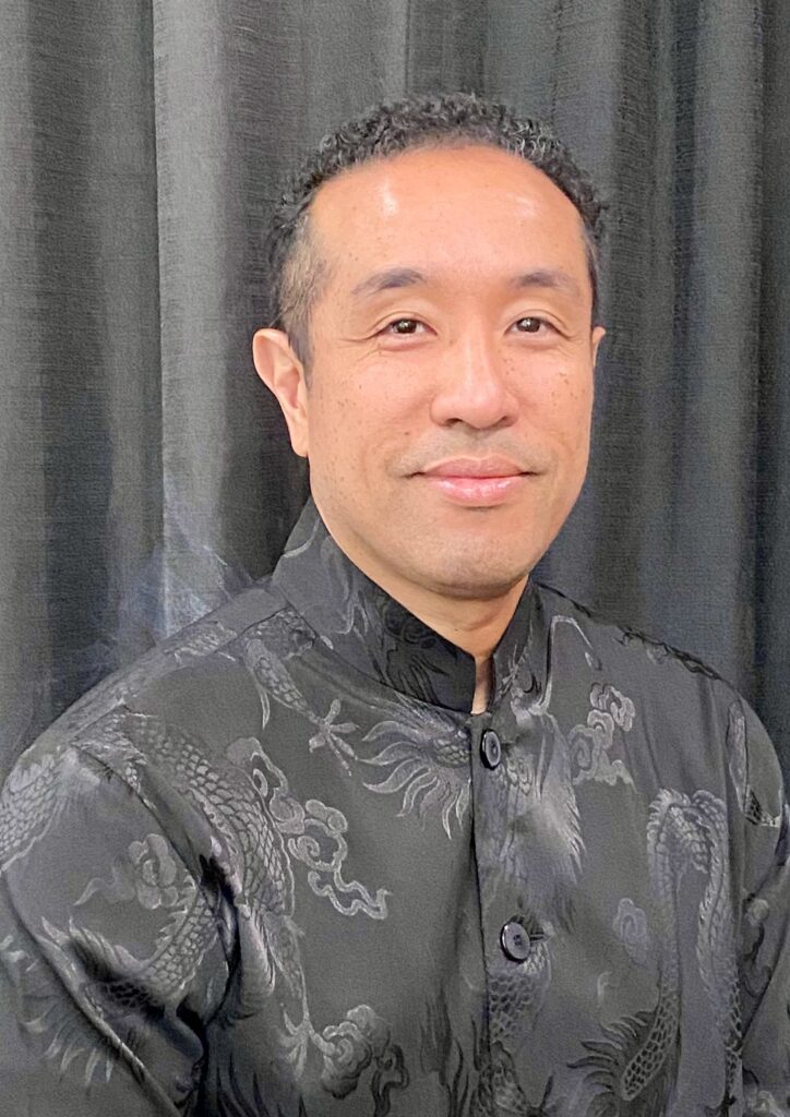 Photograph of Ibrahim “Abe” Ali wearing a gray shirt on a gray background