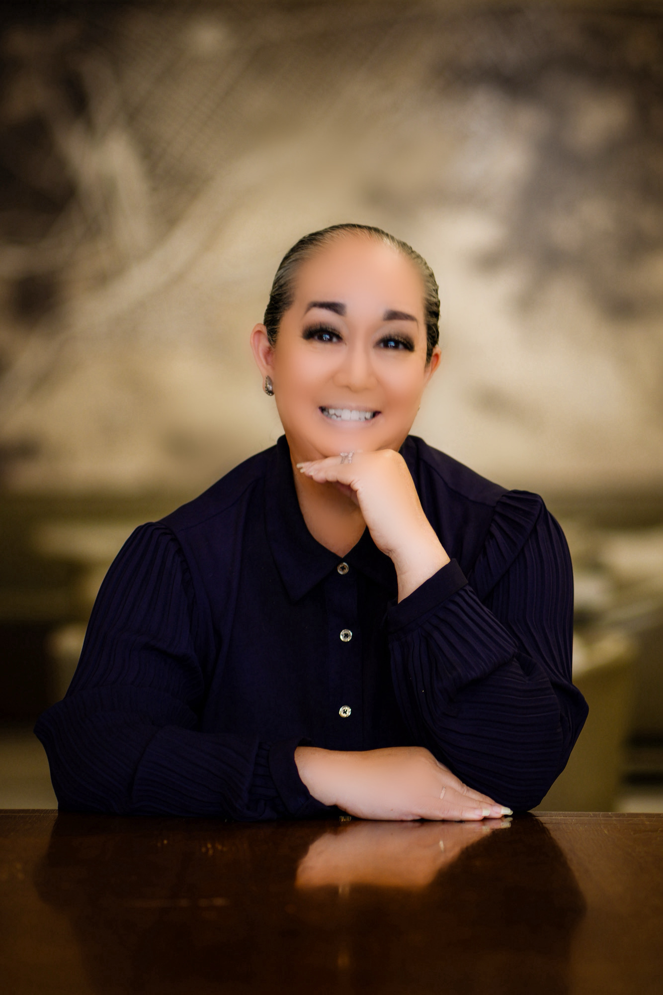 Photograph of Lori Ideta in a black jacket seated indoors